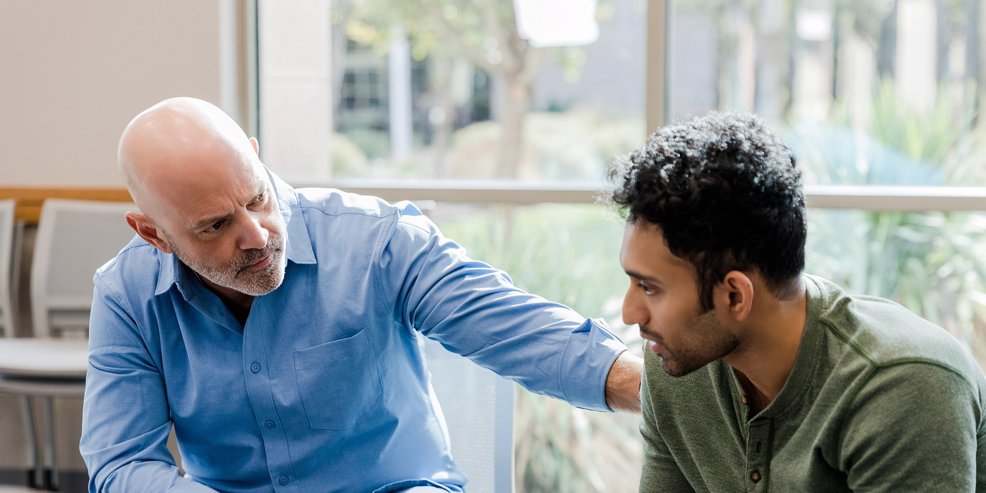 A behavioral health professional rests a consoling hand on the shoulder of a patient