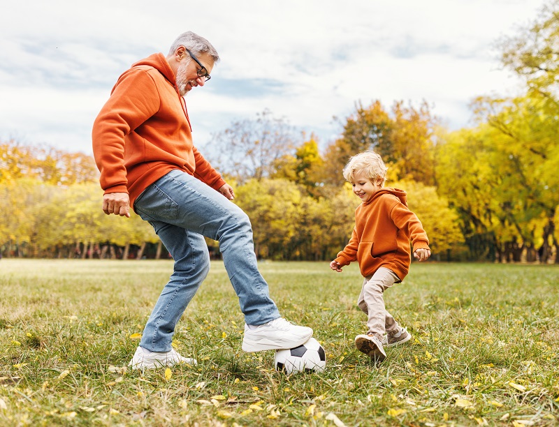 grandfather and grandson playing soccer outside in the fall