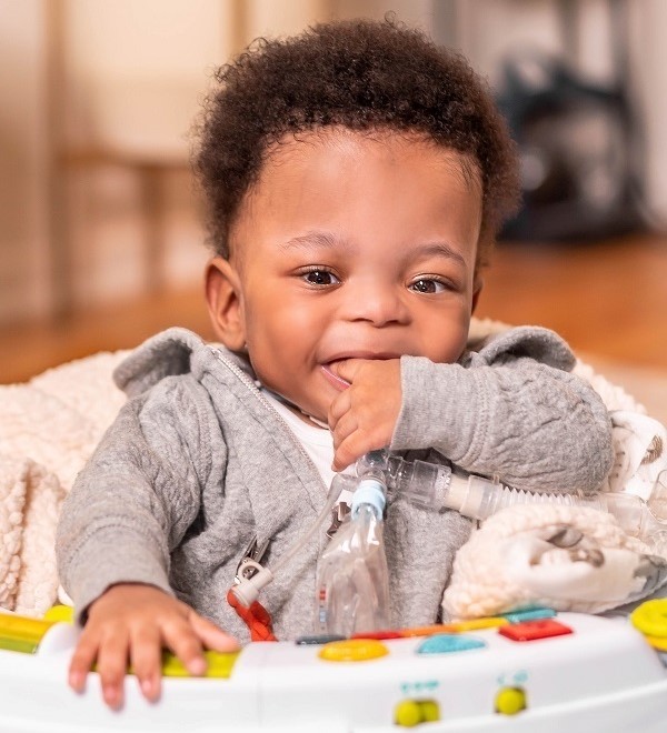 Kasan at 14 months smiling and chewing his fingers