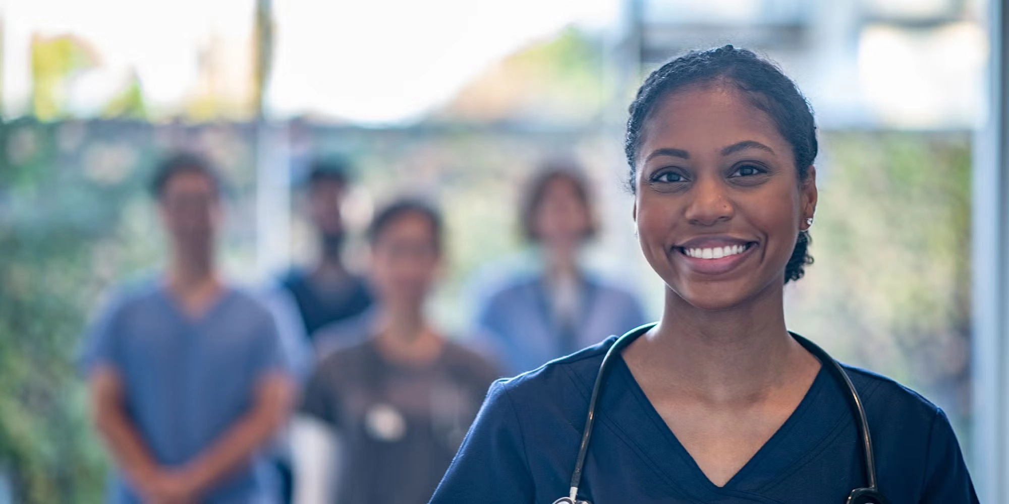 A group of residents stands in a hospital hallway. One woman is at the forefront of the image, smiling outward.