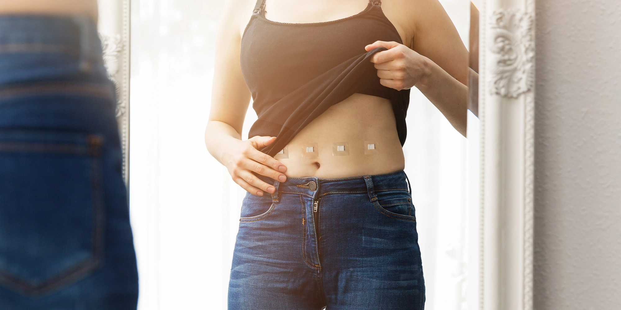 A woman partially lifts her shirt and shows off her minimal scars from robotic surgery