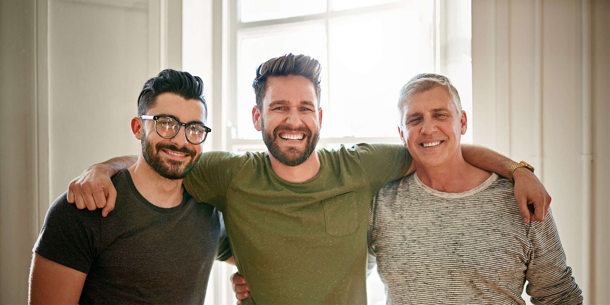 Three men of pose together with their arms around each other's shoulders
